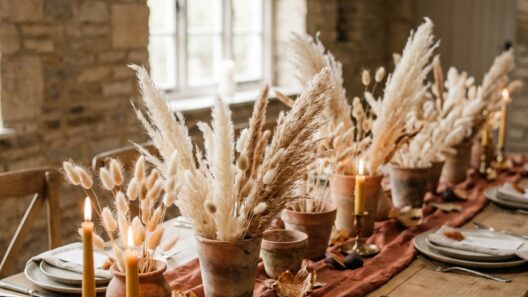Rustic fall wedding table with terracotta pots of dried grass and lit brass taper candles