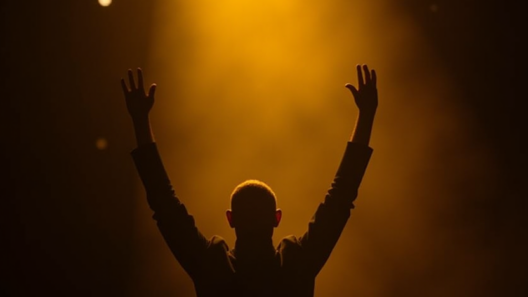Silhouette of a lone performer on a dark stage, arms raised in triumph under a single golden spotlight