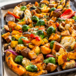 Sheet pan of roasted butternut squash, sweet potato, Brussels sprouts, carrots, red onion, pepper and cauliflower ready for weekly meal prep.