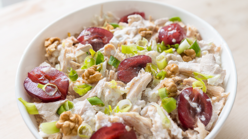 Creamy chicken salad with Greek yogurt, red grapes, walnuts and green onions in a bowl