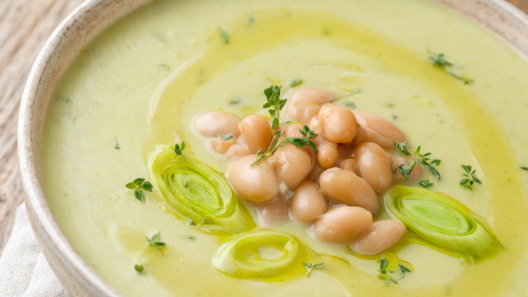 Creamy one-pot potato leek soup with white beans in a rustic bowl, topped with cannellini beans, fresh thyme and leek rings