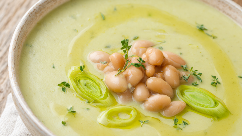 Creamy one-pot potato leek soup with white beans in a rustic bowl, topped with cannellini beans, fresh thyme and leek rings
