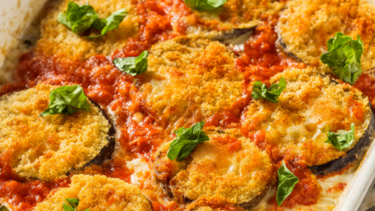 Baked eggplant Parmesan in a white baking dish with golden panko-crusted eggplant, bubbling marinara, melted mozzarella and torn basil.