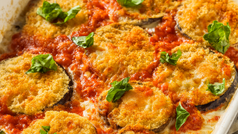 Baked eggplant Parmesan in a white baking dish with golden panko-crusted eggplant, bubbling marinara, melted mozzarella and torn basil.