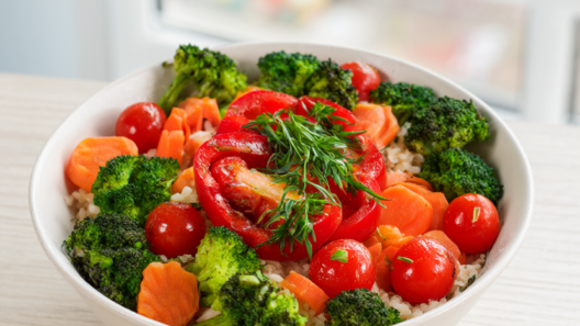 Colorful roasted vegetable bowl with broccoli, cherry tomatoes, carrots and red bell pepper over rice