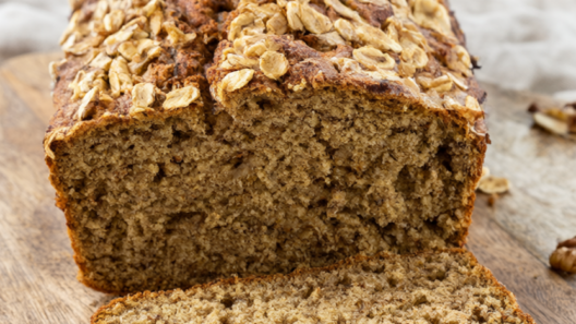 Sliced healthy banana bread with Greek yogurt and oats topped with walnuts on a rustic wooden board
