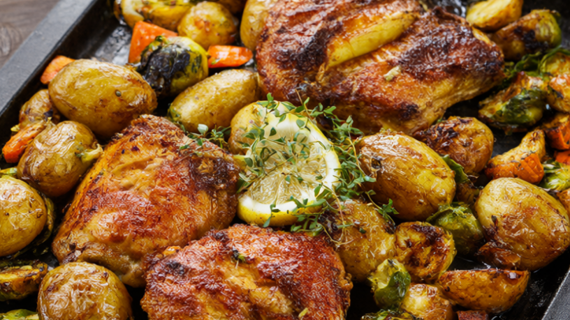 Roasted chicken thighs with baby potatoes, Brussels sprouts and carrots on a sheet pan