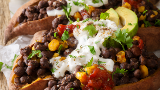 Baked sweet potatoes stuffed with black beans, corn and salsa, topped with avocado, Greek yogurt and cilantro