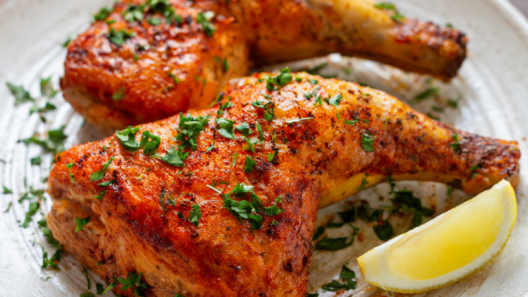 Smoked paprika roasted chicken thighs with crispy golden skin, fresh oregano, parsley and a lemon wedge