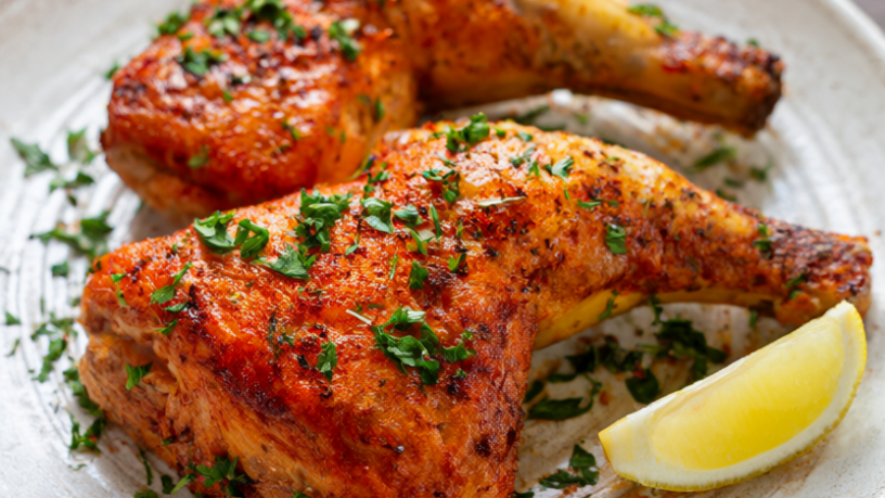 Smoked paprika roasted chicken thighs with crispy golden skin, fresh oregano, parsley and a lemon wedge