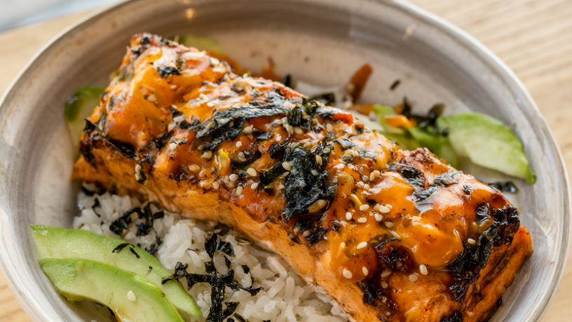 Spicy salmon rice bowl with flaky baked salmon, cucumber, avocado and sriracha mayo over jasmine rice