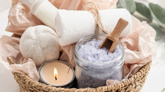 Finished DIY spa gift basket with a jar of homemade lavender bath salts, soy candle, rolled white towel and bath bomb on a bathroom counter