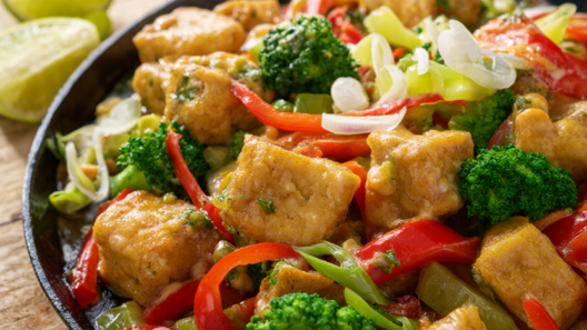 Crispy peanut tofu stir fry with broccoli and red bell pepper in a cast-iron skillet