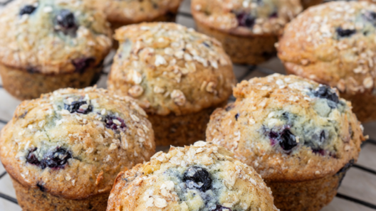 Golden blueberry oatmeal muffins with bursting blueberries on a wire cooling rack