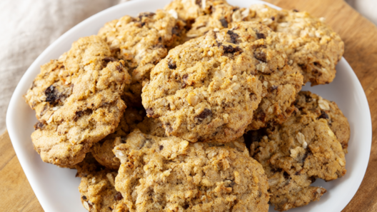 Golden holiday cookies with dark chocolate chunks and rolled oats on a rustic wooden board