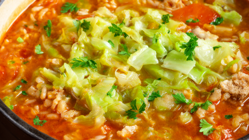 Rustic Dutch oven of one-pot cabbage roll soup with green cabbage, ground turkey and brown rice in a rich tomato broth.