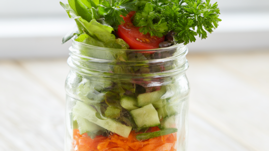 Layered mason jar salad with chickpeas, carrots, cucumber, cherry tomatoes and greens over creamy dressing