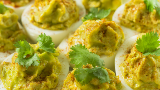 Avocado deviled eggs on a platter, garnished with cilantro and smoked paprika