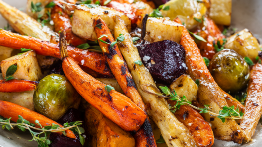 Roasted winter vegetables: carrots, parsnips, beets, Brussels sprouts and butternut squash on a rustic table