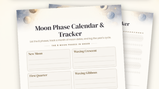 Flat-lay of two printed moon phase calendar pages on deep navy linen with a cream notebook, brass moon-phase garland, lit candle and star confetti