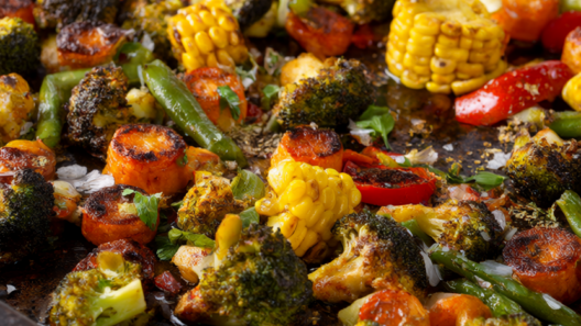 Roasted frozen mixed vegetables with browned edges on a dark sheet pan, garnished with parsley