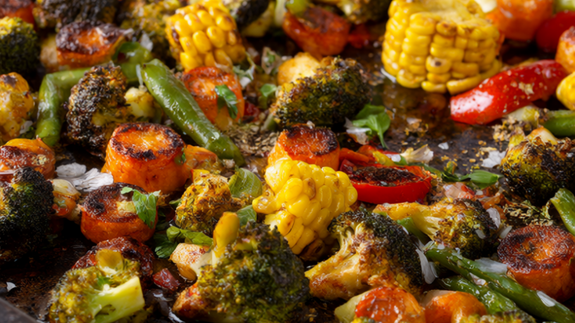 Roasted frozen mixed vegetables with browned edges on a dark sheet pan, garnished with parsley