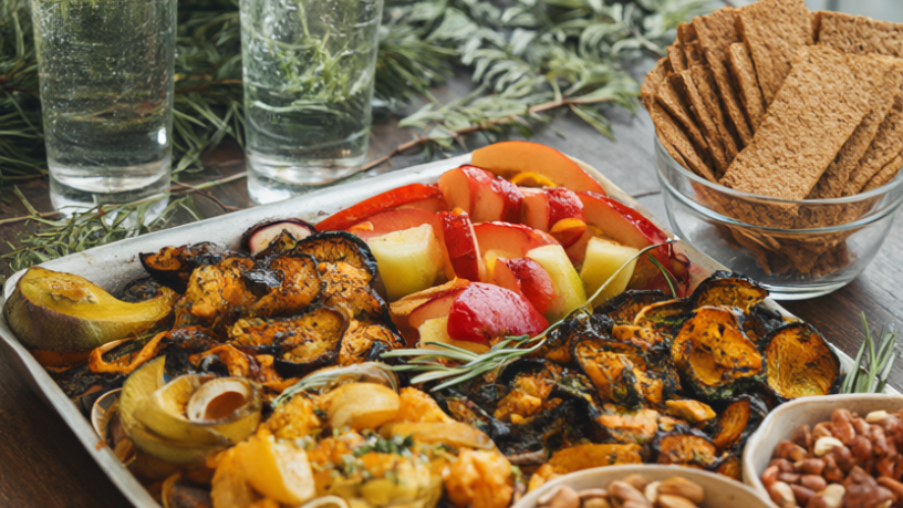 Holiday party table with roasted vegetables, fresh fruit, nuts, whole-grain crackers and sparkling water