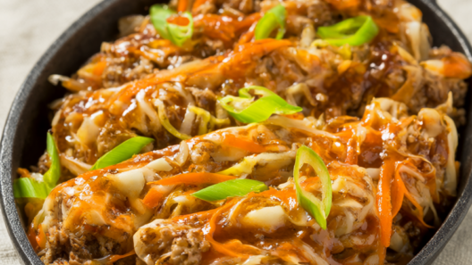 Egg roll in a bowl with ground turkey, cabbage and carrots in a cast-iron skillet, topped with green onions.
