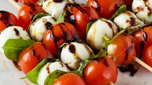 Caprese skewers with balsamic glaze: cherry tomatoes, mozzarella and basil on wooden skewers.