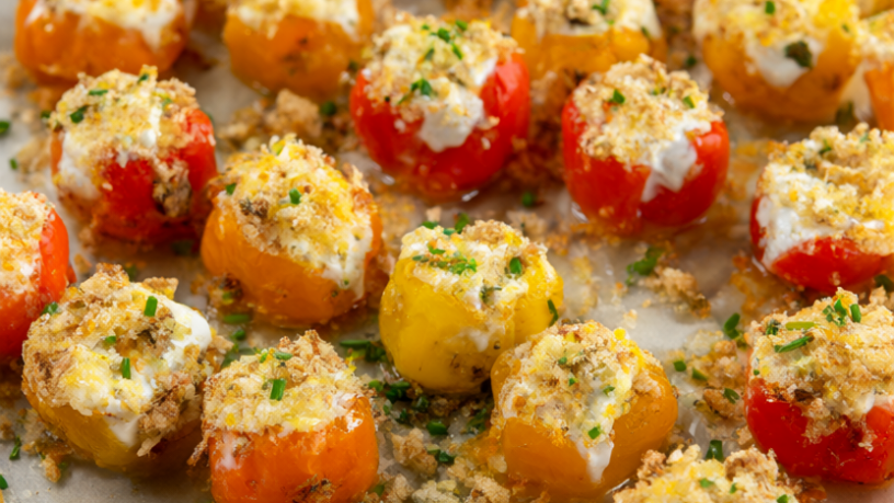 Roasted stuffed mini sweet peppers on a platter with goat cheese filling, golden panko and chives.