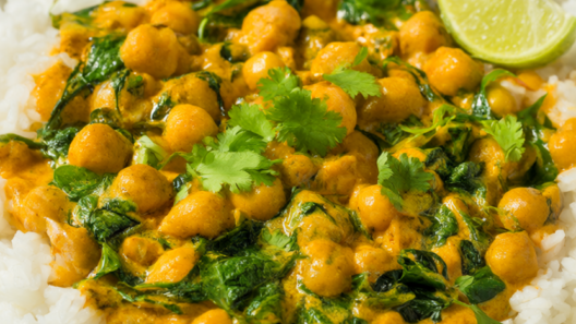 Creamy coconut chickpea curry with spinach served over white rice in a ceramic bowl