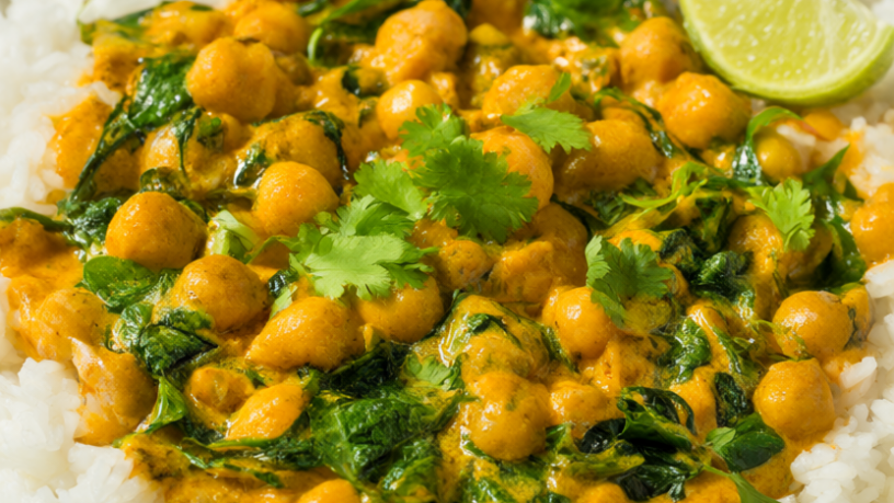 Creamy coconut chickpea curry with spinach served over white rice in a ceramic bowl